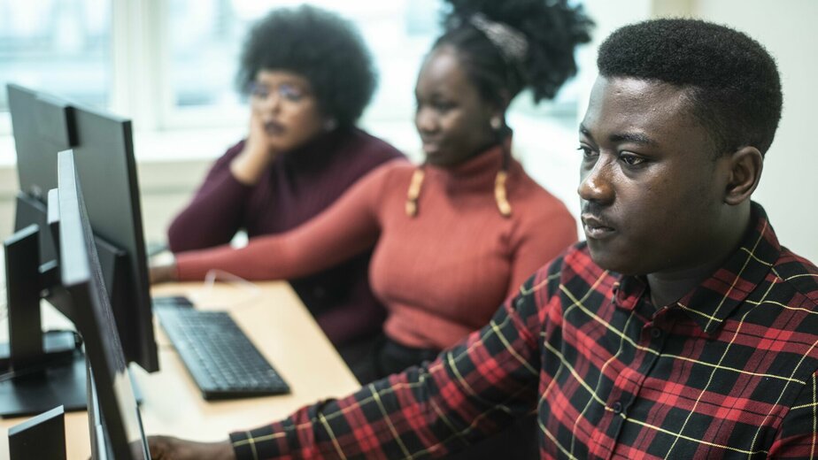 drie studenten aan twee computers
